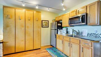 Una cocina con armarios de madera, un microondas de acero inoxidable y un refrigerador.