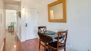 Un couloir comprenant un coin repas avec une table et des chaises, une porte et un miroir fixé au mur.