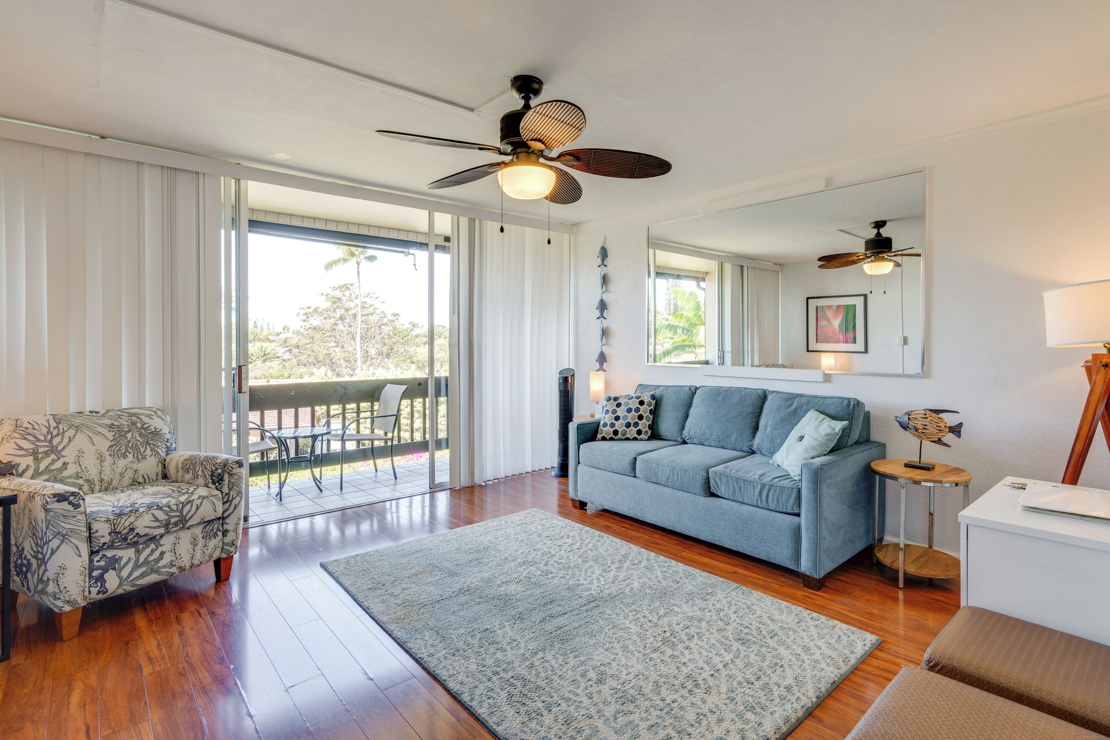 A spacious living room with a large sofa, a patterned armchair, and a wooden floor.