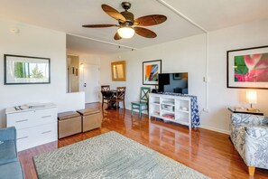 Una sala de estar con ventilador de techo, televisor, sofá, mesa de centro y comedor con sillas y mesa.
