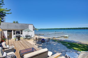 Une terrasse avec coin salon extérieur, un barbecue et vue sur un lac.