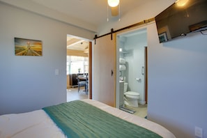 Une chambre avec un lit, une porte coulissante donnant accÚs à une salle de bain et un tableau accroché au mur.