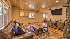 A spacious living room with a leather couch, wooden coffee table, and a stone accent wall. - South Lake Tahoe Cabin ~ 7 Mi to Ski Resort! (South Lake Tahoe)