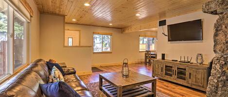 A spacious living room with a leather couch, wooden coffee table, and a stone accent wall.