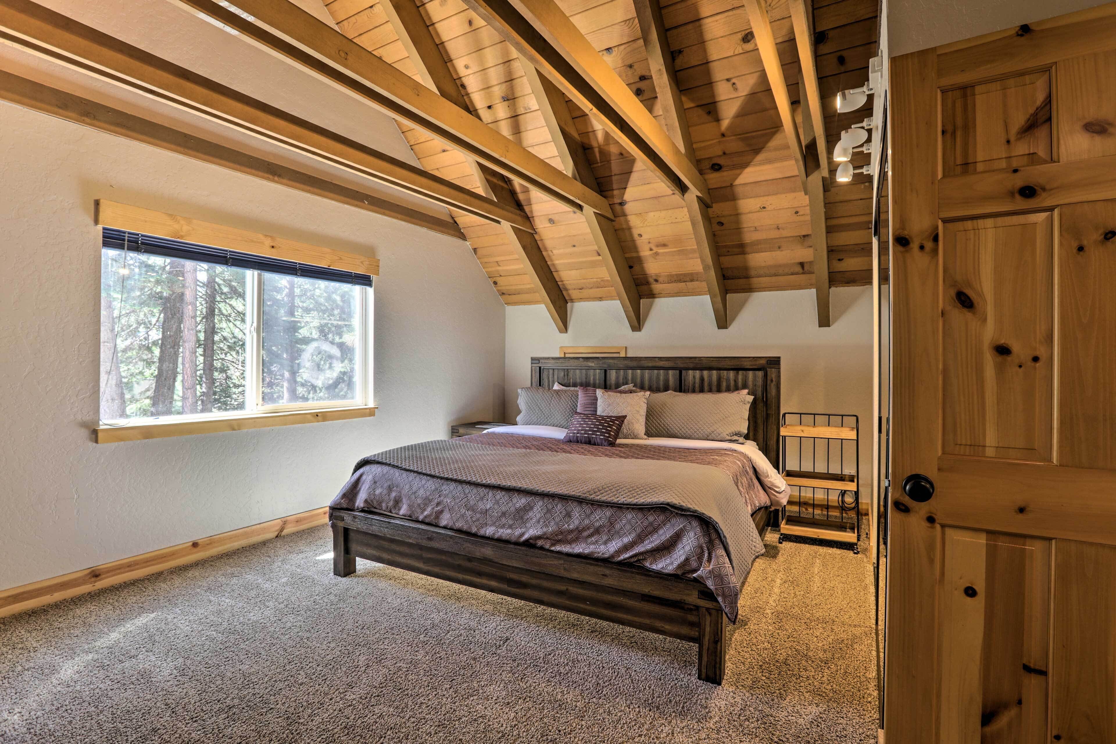Ein Schlafzimmer mit Holzboden, einem großen Fenster, einem Bett und einer Tür.