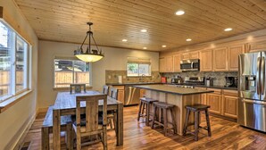 A spacious kitchen with wooden cabinets, a stainless steel refrigerator, and a large island with stools. - South Lake Tahoe Cabin ~ 7 Mi to Ski Resort! (South Lake Tahoe)