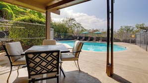 Une terrasse extérieure avec une piscine, des chaises et des parasols.