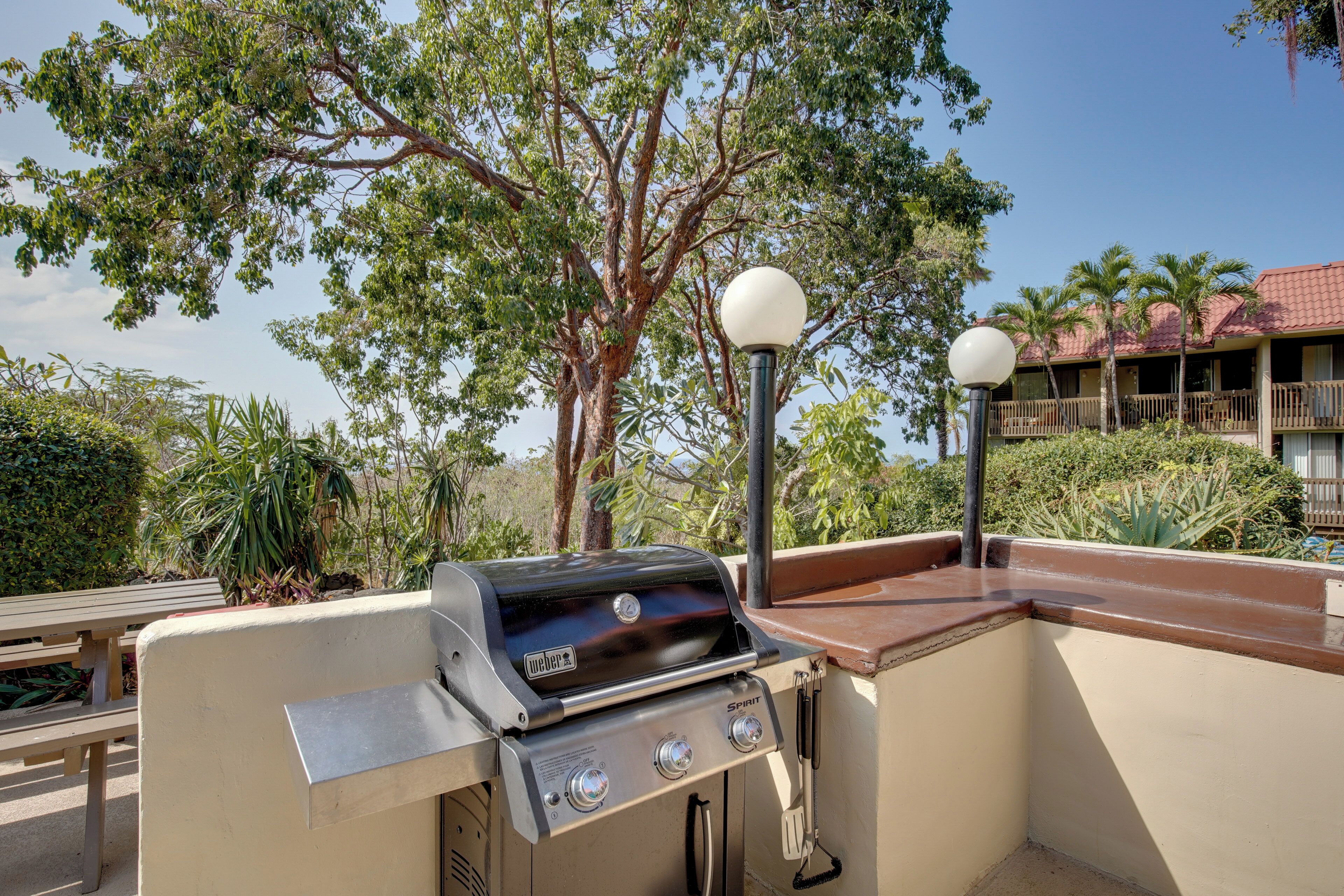 Un área de parrilla al aire libre con una barbacoa Spirit, un banco y un farol.