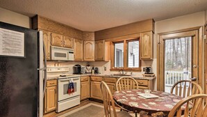 Une cuisine avec des meubles de rangement en bois, un réfrigérateur, un four à micro-ondes, un four et une table à manger avec des chaises.