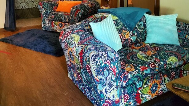 A cozy bedroom with a colorful patterned sofa, a small bedside table, and a lamp. - Charming 2-bedroom house with AC, WiFi in delightful Brainerd (Brainerd)