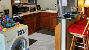 A compact kitchen with a washing machine, microwave, sink, and wooden cabinets. - Charming 2-bedroom house with AC, WiFi in delightful Brainerd (Brainerd)