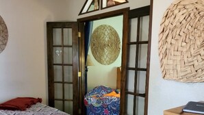 A bedroom with a bed, a wooden dresser, a woven wall hanging, and a patterned chair. - Charming 2-bedroom house with AC, WiFi in delightful Brainerd (Brainerd)
