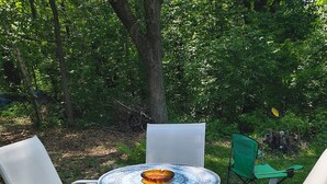 A round table with a mosaic tablecloth, surrounded by two white chairs with mesh backs. - Charming 2-bedroom house with AC, WiFi in delightful Brainerd (Brainerd)