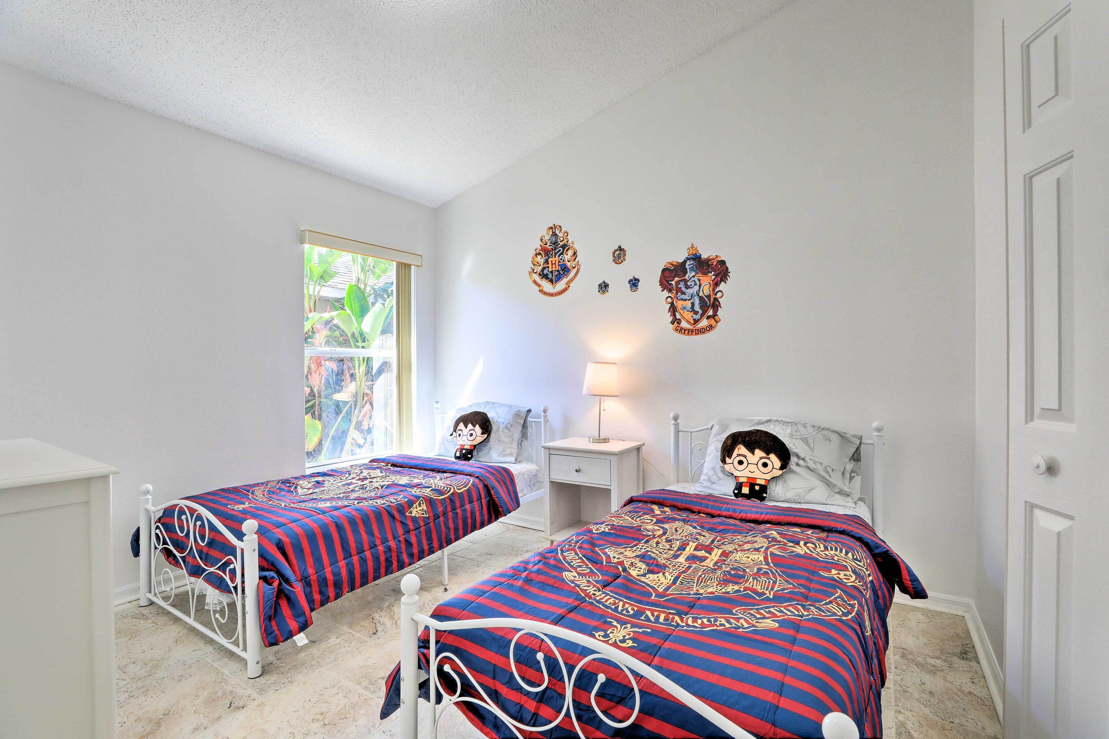 A bedroom with two beds, a window, a nightstand, and wall decorations.