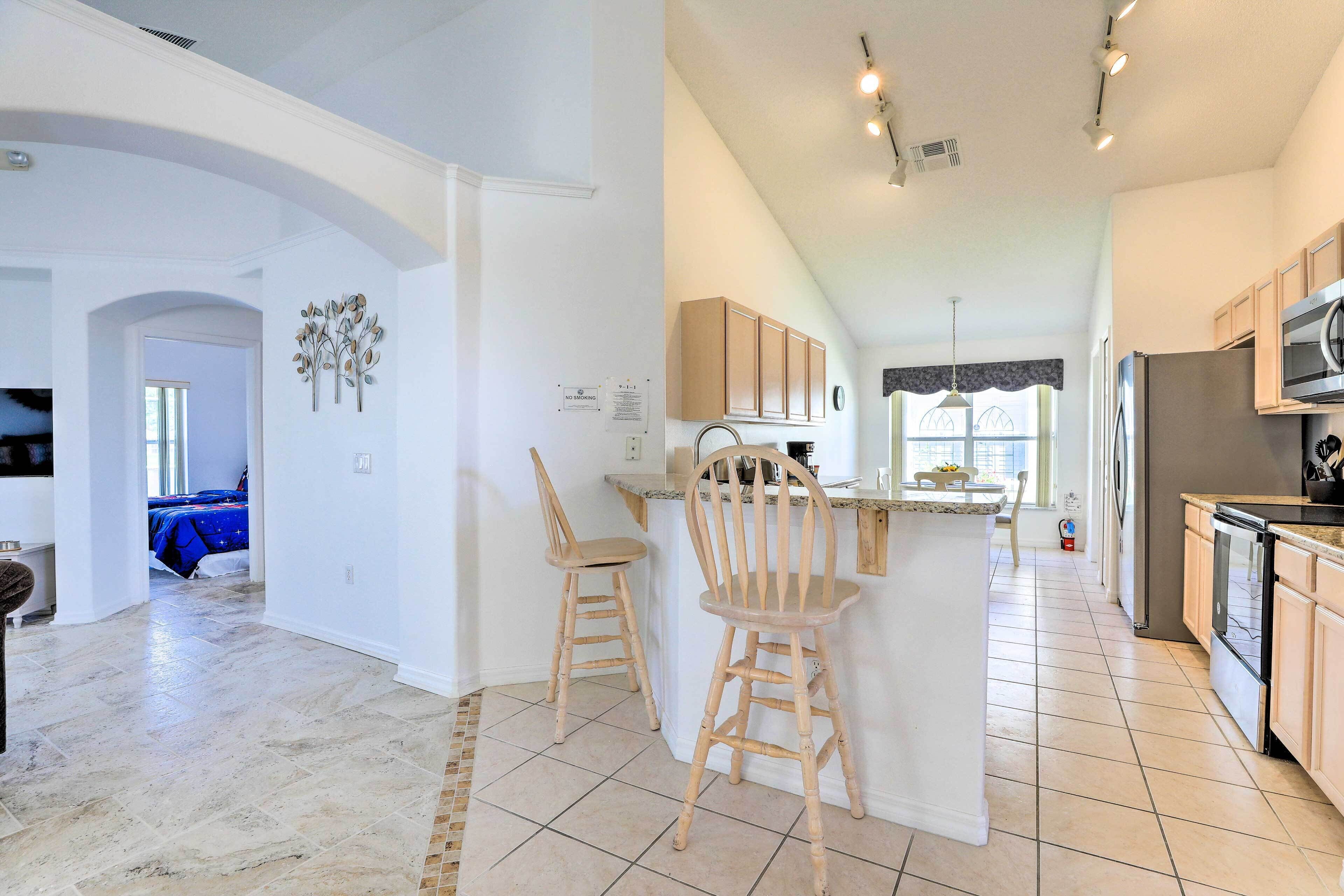 A spacious kitchen with a central island, wooden chairs, and a dining area.