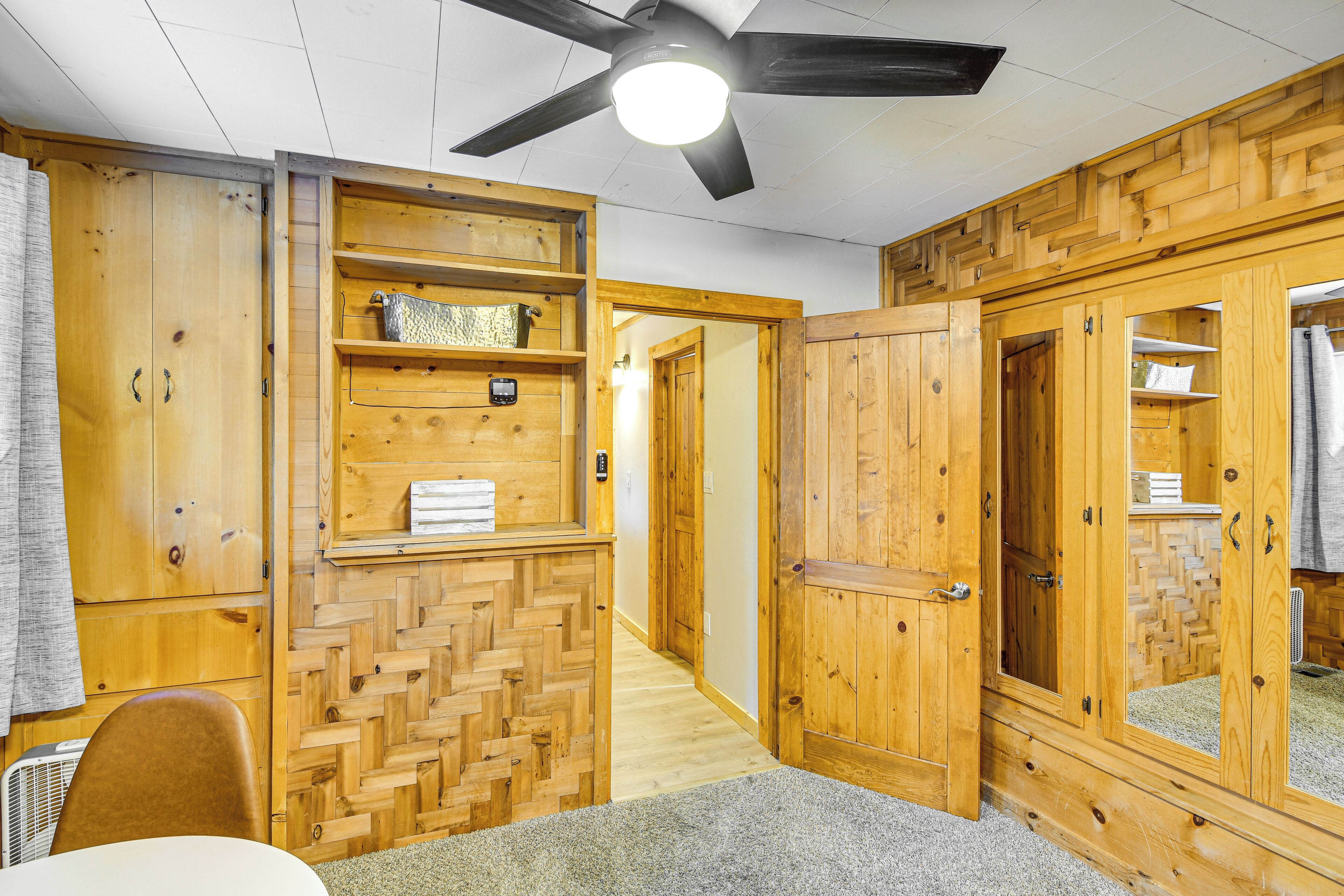 A room with wooden walls, a ceiling fan, and a carpeted floor.