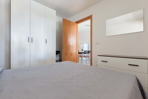 A bedroom with a bed, a wardrobe, a mirror, and a door leading to a bathroom.