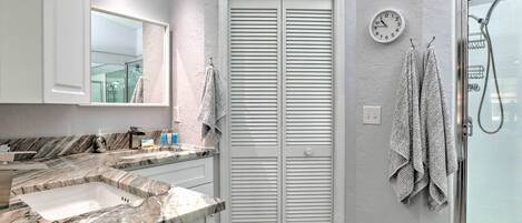 Un baño con dos lavamanos, un espejo, un reloj y una ducha.