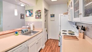 A compact kitchen with a sink, stove, and cabinets. - Waikoloa Village Home in Resort Golf Community (Waikoloa)