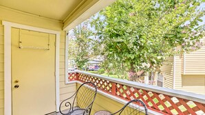A porch with two metal chairs and a small table, a yellow door, and a red lattice railing. - Waikoloa Village Home in Resort Golf Community (Waikoloa)