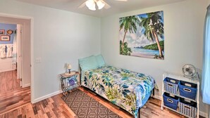 A bedroom with a bed, a ceiling fan, a wall-mounted picture, and a storage unit with bins. - Waikoloa Village Home in Resort Golf Community (Waikoloa)