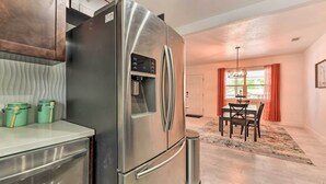 A modern kitchen with a stainless steel refrigerator, wooden cabinets, and a dining area with a table and chairs. - Bright, Pet-friendly Retreat in Avon Park! (Avon Park)