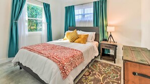 A bedroom with a bed, a nightstand, a lamp, a dresser, and a window with curtains. - Bright, Pet-friendly Retreat in Avon Park! (Avon Park)