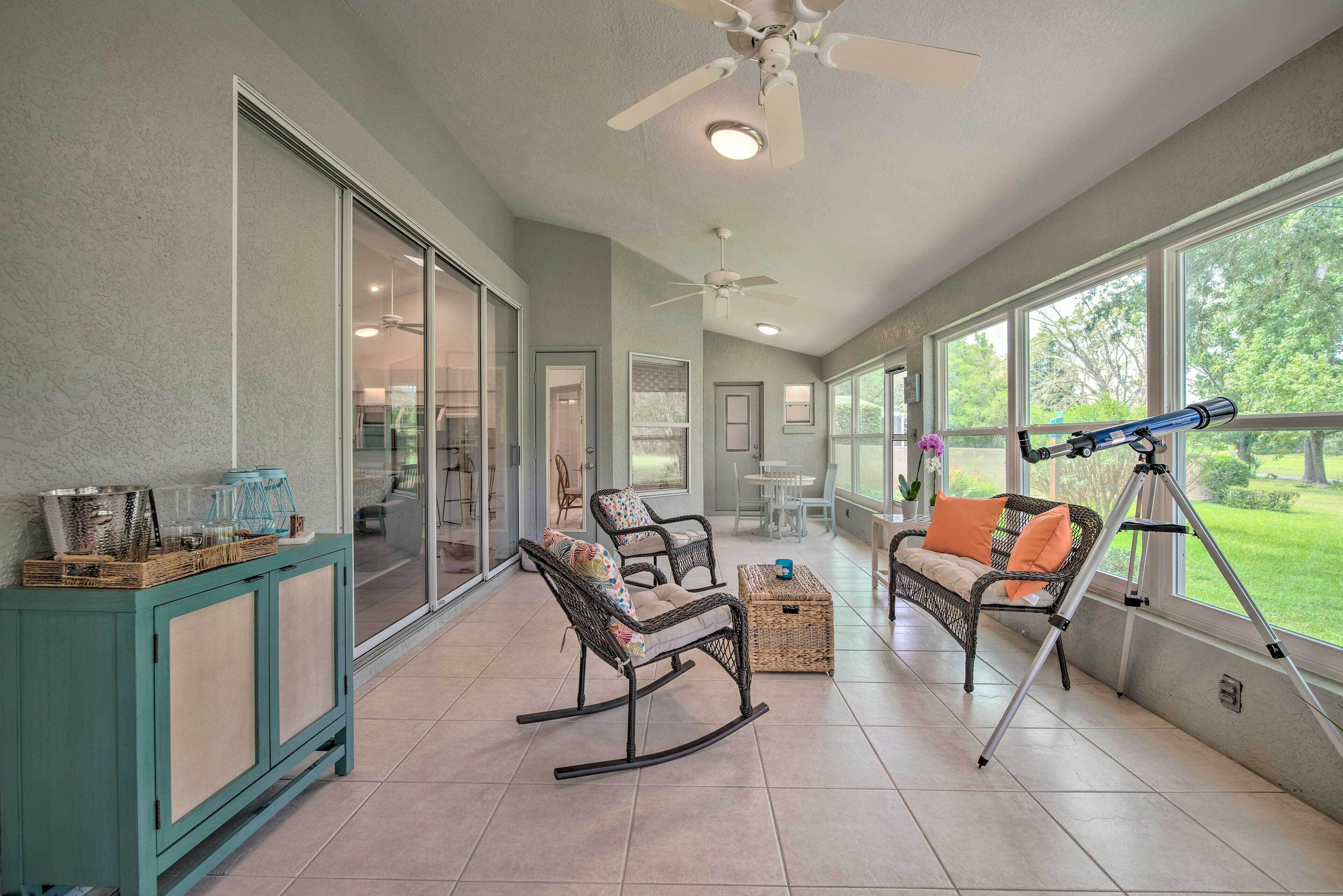 Un patio amplio con mecedoras de mimbre, un telescopio y un mueble de estilo teal.