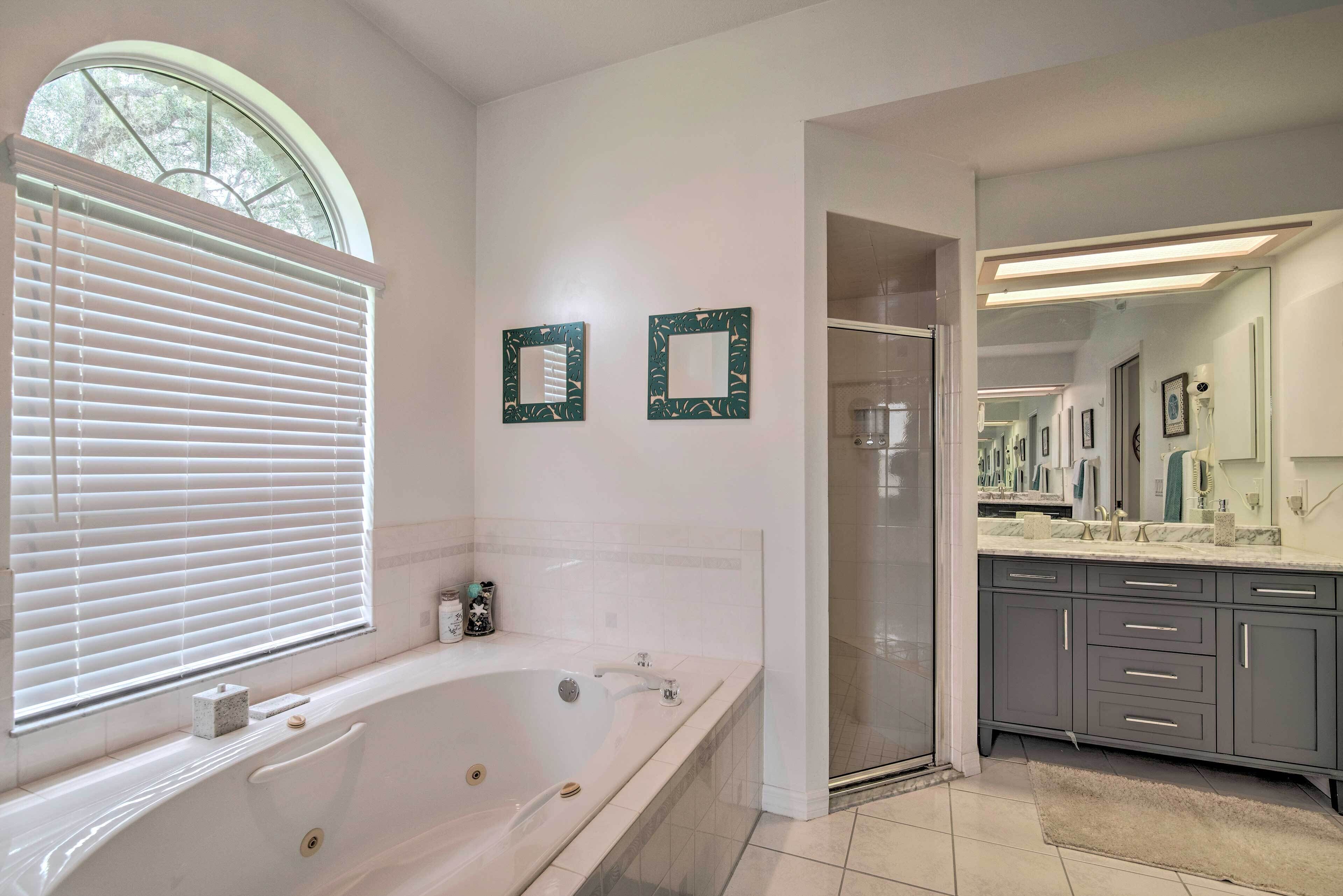 A modern bathroom with a large bathtub, a walk-in shower, and a vanity with a mirror.