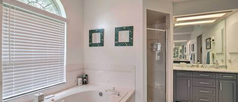 A modern bathroom with a large bathtub, a walk-in shower, and a vanity with a mirror.