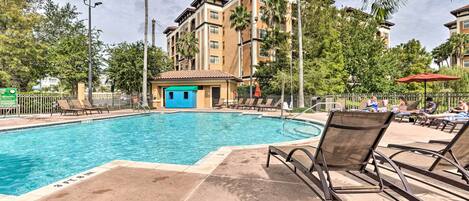A swimming pool with lounge chairs and a small building with a blue door.