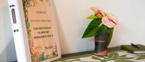Un cuaderno con diseño floral y texto, junto a una maceta con flores rosadas.