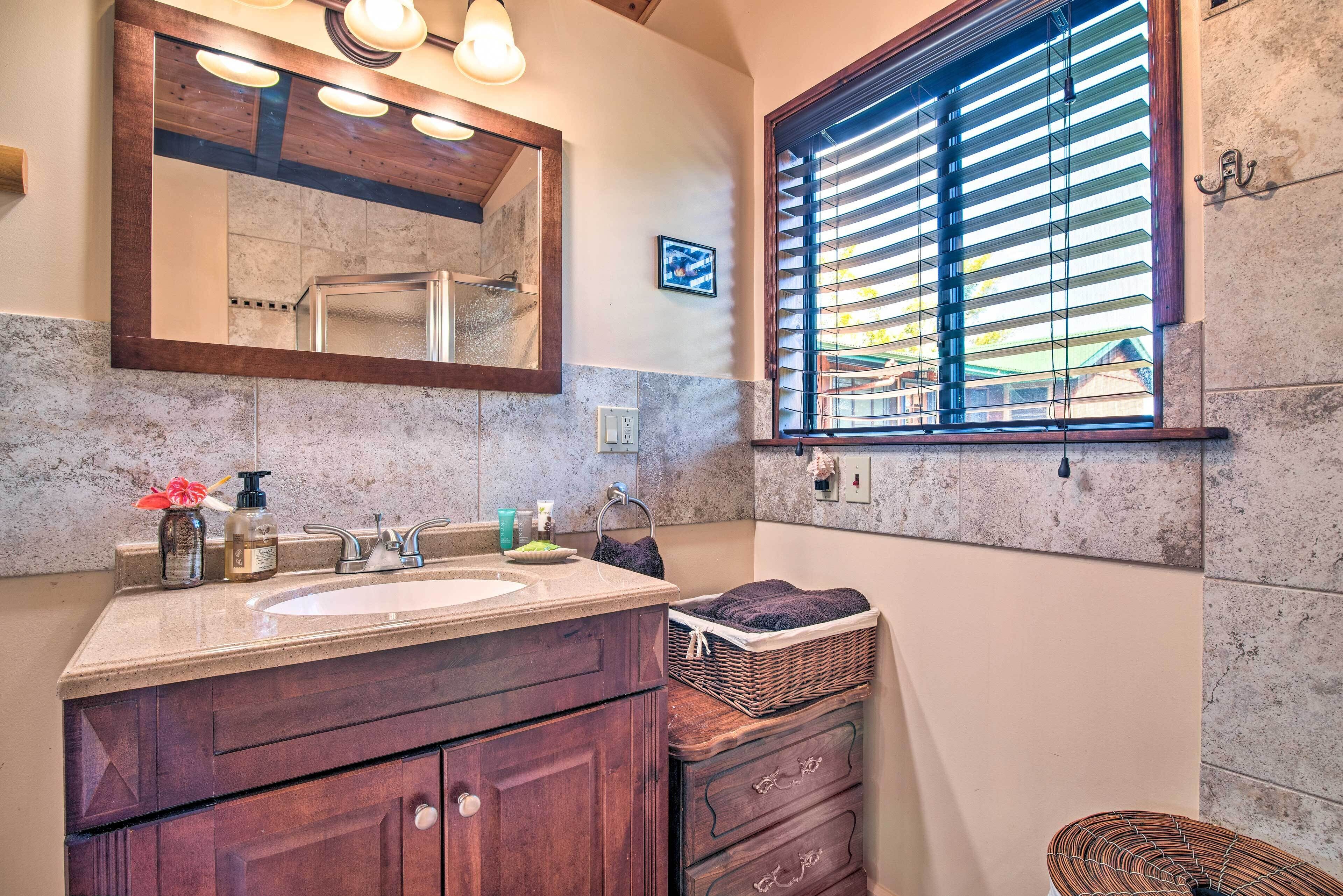 A bathroom with a large mirror, a sink, and a window with blinds.