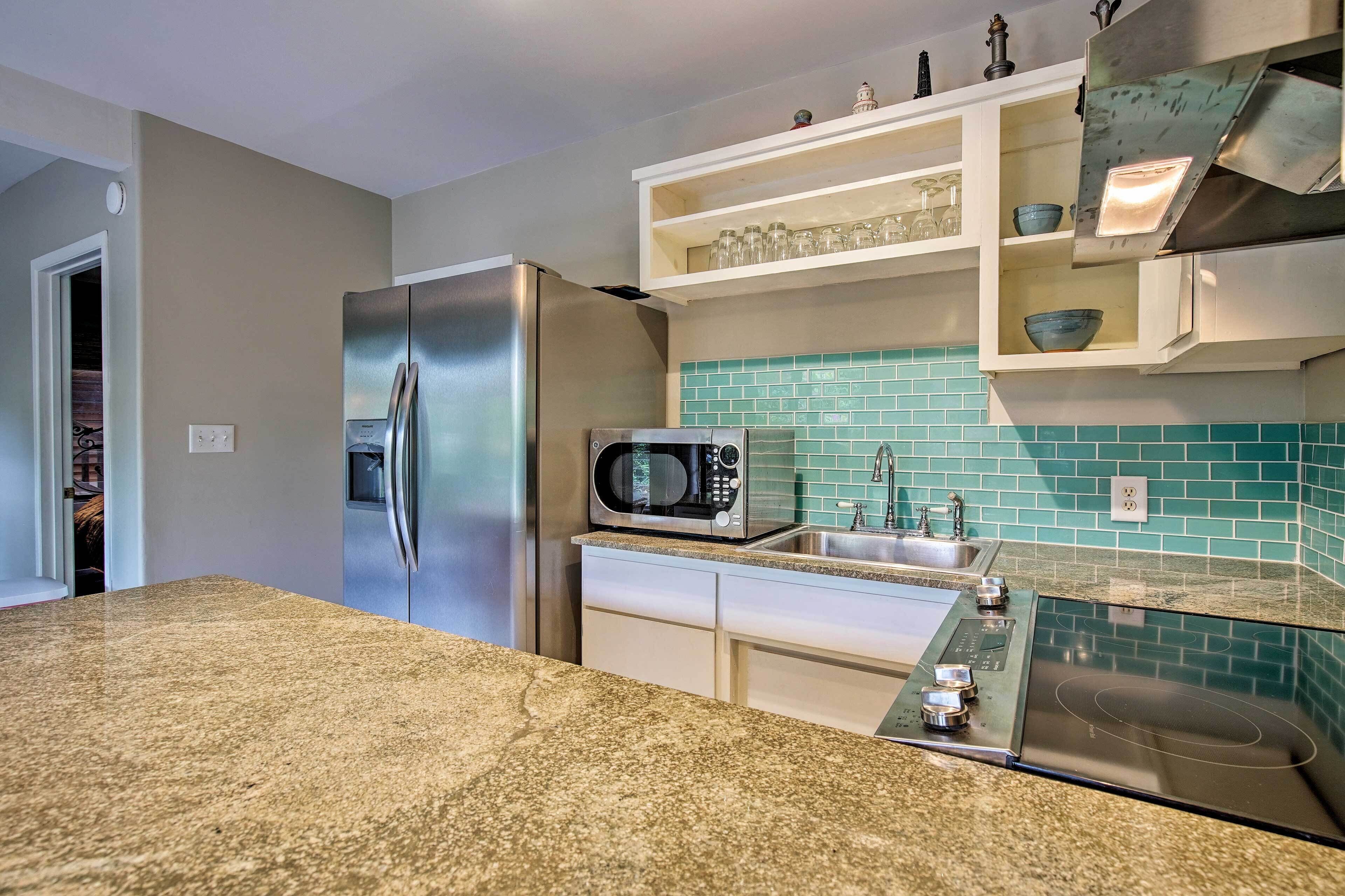 Una cocina con un refrigerador de acero inoxidable, un microondas, un horno empotrado y un lavamanos.