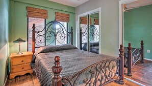 A bedroom with a bed, wooden nightstand, and a ceiling fan.