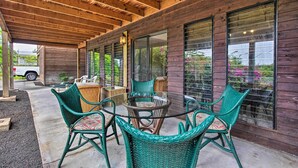 A covered patio with wicker furniture and large windows.