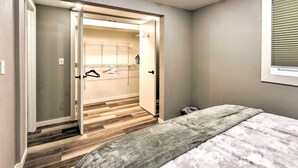 A bedroom with a bed, a gray blanket, a wooden floor, a closet with a mirror, and a window with blinds. - Walk to Lake Pepin: Charming Retreat w/ Deck (Pepin)