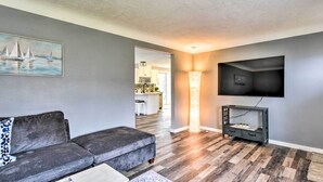 A modern living room with a grey sofa, a coffee table, and a flat-screen TV mounted on the wall. - Walk to Lake Pepin: Charming Retreat w/ Deck (Pepin)
