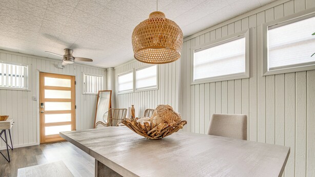 A dining area with a long table, a woven light fixture, and a ceiling fan. - Walkable Florida Duplex: 2 Blocks to Cocoa Beach! (Cocoa Beach)