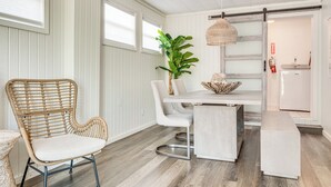 A dining area with a wicker chair, a white table, and a hanging light fixture. - Walkable Florida Duplex: 2 Blocks to Cocoa Beach! (Cocoa Beach)