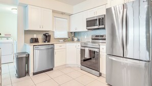 A modern kitchen with white cabinets, stainless steel appliances, a dishwasher, and a microwave. - Walkable Florida Duplex: 2 Blocks to Cocoa Beach! (Cocoa Beach)