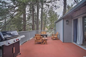 Eine Außenpatio mit Grill, Holzstühlen und einem Tisch.