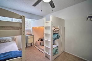 Ein Schlafzimmer mit Etagenbetten, einem Schreibtisch, einem Regal und einem Deckenventilator.
