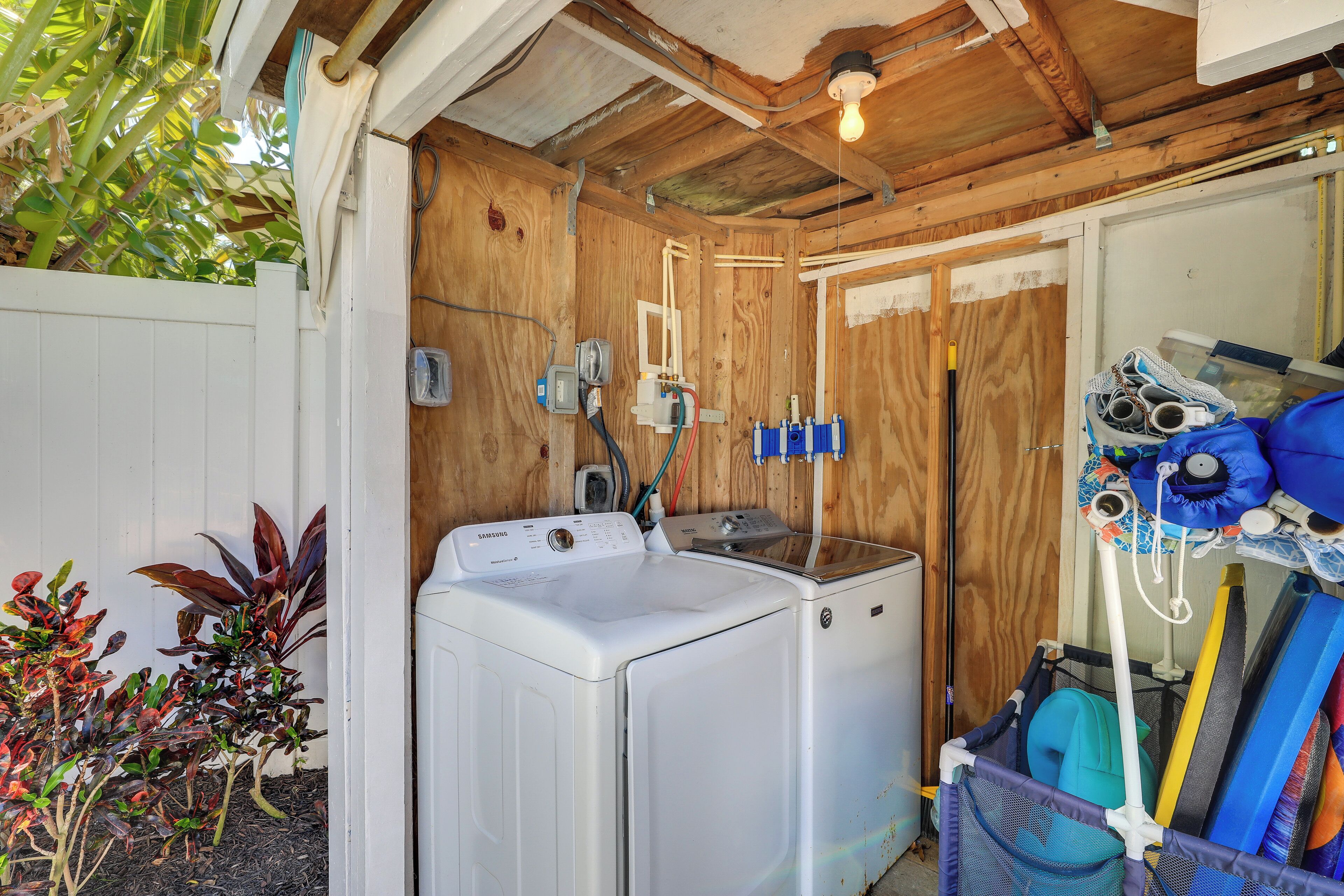 A laundry area with a white washer and dryer, wooden walls, and a ceiling light.