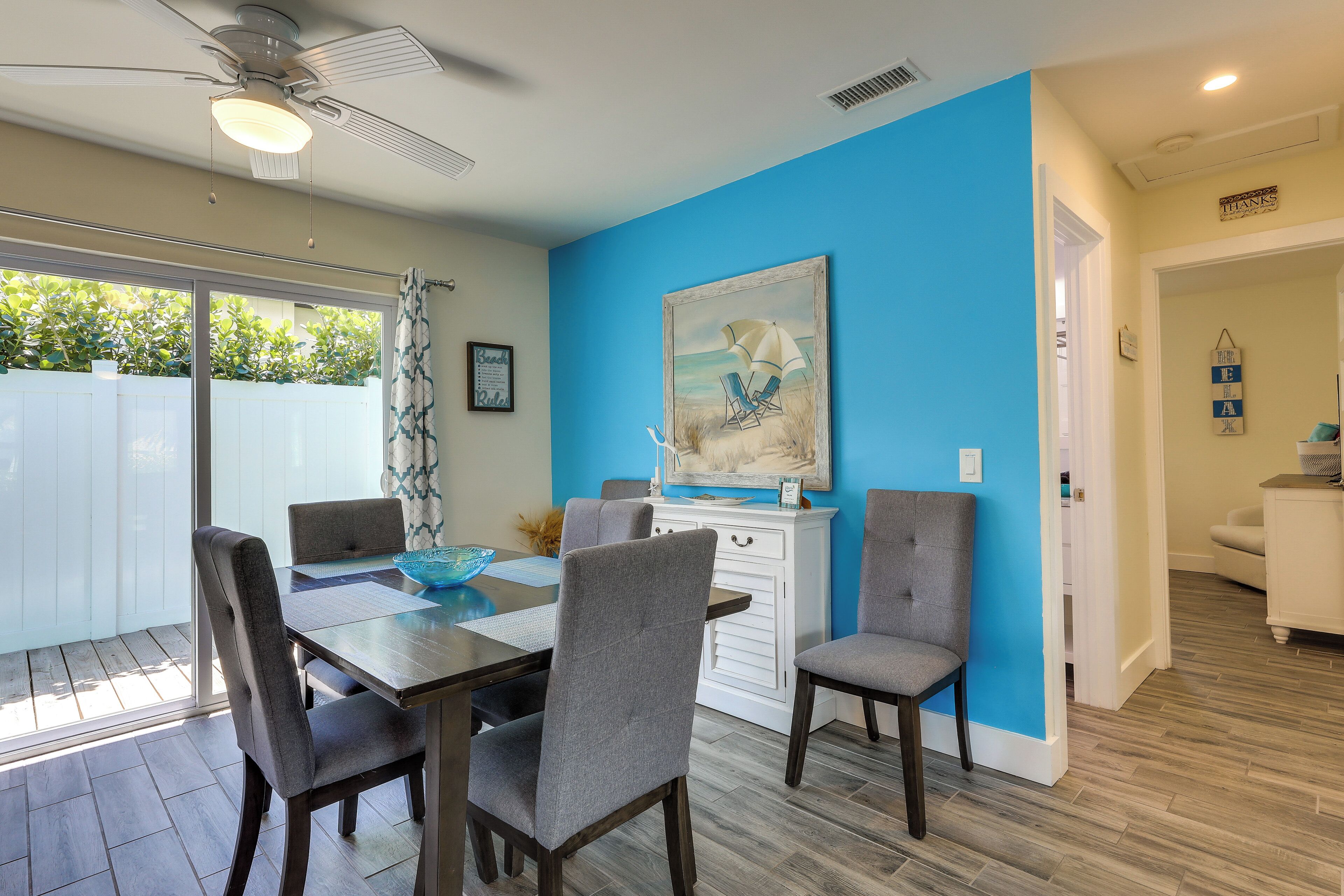 A dining area with a table and chairs, a ceiling fan, and a painting on the wall.