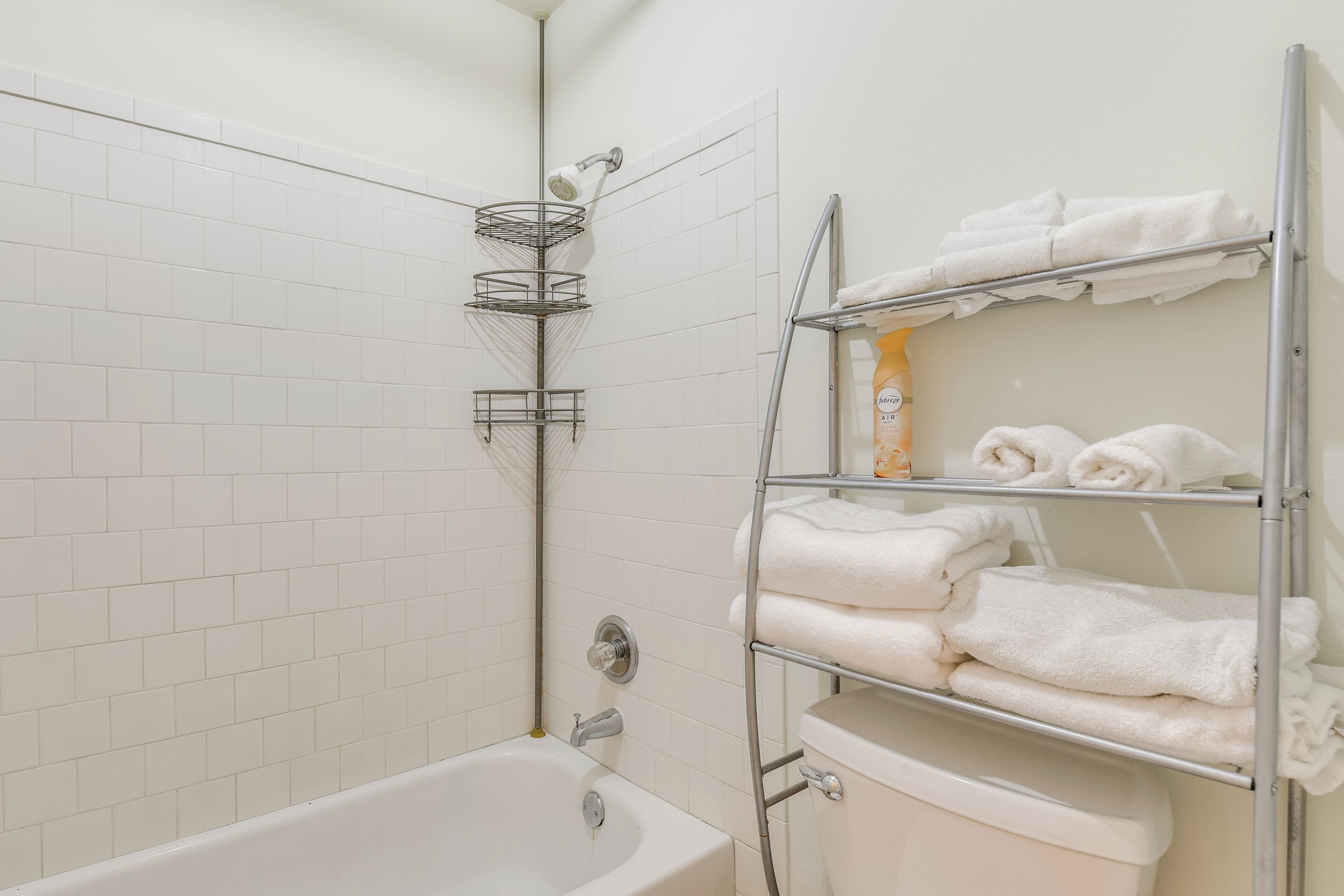 Ein Badezimmer mit einer weißen Badewanne, einer Dusche und einem Handtuchhalter mit ordentlich gefalteten Handtüchern.