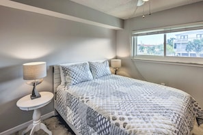 Un dormitorio con cama, dos lámparas de noche, una ventana y vistas a edificios.