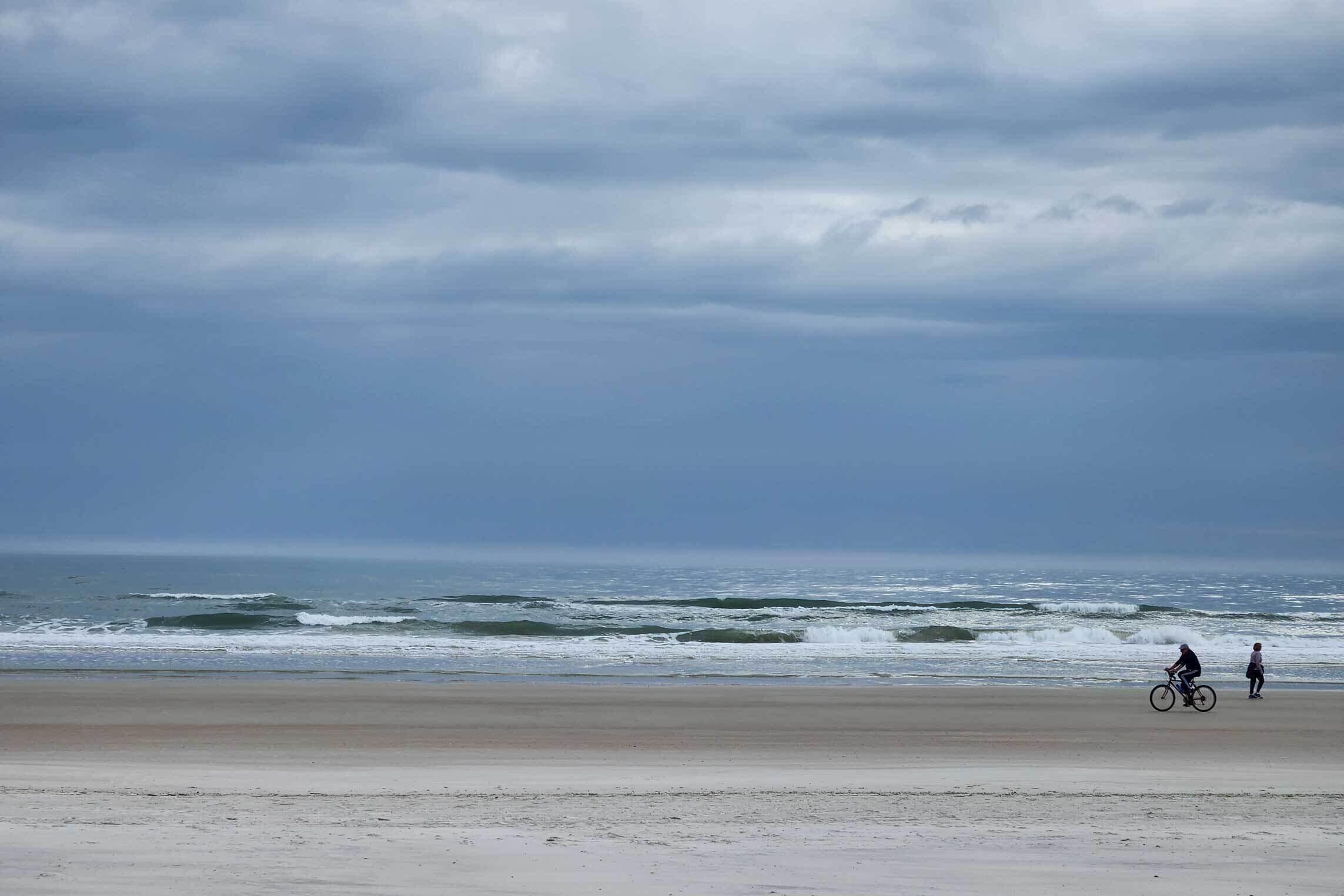En strand med sandet bredde og bølger i baggrunden.