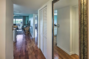 A hallway with wooden flooring, a dining area with chairs and a table, and a large mirror on the wall. - Sunny St Augustine Condo w/ Community Pool! (St. Augustine)