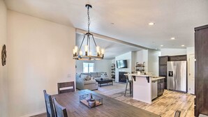 A modern kitchen with a central island, stainless steel appliances, and a dining area with a wooden table and chairs.